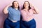Young plus size twins wearing casual clothes smiling pointing to head with both hands finger, great idea or thought, good memory
