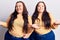 Young plus size twins wearing casual clothes smiling showing both hands open palms, presenting and advertising comparison and