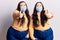 Young plus size twins wearing medical mask approving doing positive gesture with hand, thumbs up smiling and happy for success