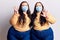 Young plus size twins wearing medical mask showing and pointing up with fingers number eight while smiling confident and happy