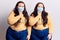Young plus size twins wearing medical mask touching mouth with hand with painful expression because of toothache or dental illness