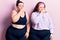Young plus size twins wearing sportswear smelling something stinky and disgusting, intolerable smell, holding breath with fingers