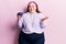 Young plus size woman holding blueberries celebrating achievement with happy smile and winner expression with raised hand