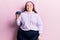 Young plus size woman holding blueberries looking positive and happy standing and smiling with a confident smile showing teeth