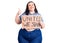 Young plus size woman holding united we stand banner smiling happy and positive, thumb up doing excellent and approval sign