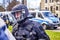 Young police officer in black uniform and protective suit with visor down on helmet at the edge of a demonstration