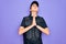 Young police woman wearing security bulletproof vest uniform over purple background begging and praying with hands together with