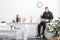 Young policeman sitting on table, drinking orange juice and using laptop