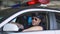 Young policeman wearing sunglasses in car and smiling at camera, important job