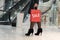 Young posh fashionable girl goes to a large clothing store with shopping bags. The inscription sale on the red bag. Shopping