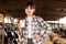 Young positive female dairy farm worker standing with glass of fresh milk