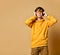 Young positive teen boy in yellow hoodie, sunglasses and headphones standing and smiling