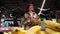 Young positive woman buys bananas in the fruit section of the supermarket.