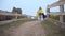 Young pregnant mom and her little daughter in similar yellow coat walking with big black doberman along the fence in
