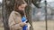 Young pregnant serious girl in beige vintage rare coat and royal blue tshirt tapping her smartphone on countryside