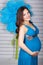 Young pregnant woman with big blue flowers in studio