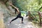 Young pregnant woman in black sports overalls practicing yoga, doing virabhadrasana exercise, warrior pose, exercising in the park