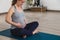 Young pregnant woman doing prenatal yoga in a studio holding belly