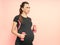 Young pregnant woman exercises with dumbell. Working out and fitness on last months of pregnancy and healthy motherhood concept.