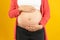 Young pregnant woman expecting a baby. Pregnant woman touching big belly with hands on yellow background.