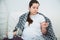 Young pregnant woman feel sick, high fever, sitting on sofa indoors