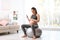 Young pregnant woman in fitness clothes lifting dumbbell