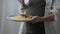 Young pregnant woman with food plate standing indoors with fork. Unrecognizable Caucasian hungry expectant having lunch