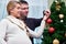 Young pregnant woman and happy father decorating christmas tree