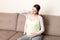 Young pregnant woman with headache sitting on sofa. Pregnancy expectation concept