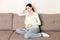 Young pregnant woman with headache sitting on sofa. Pregnancy expectation concept