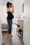 young pregnant woman at home taking a selfie on mirror with camera. cute beagle dog besides
