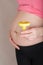 Young pregnant woman keeps empty urine container close to her belly