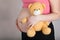 Young pregnant woman keeps plush brown teddy bear