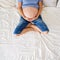 Young pregnant woman, lying in bed with tablet, book, coffee and