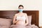 Young pregnant woman in protective medical mask is staying in bed because of coronavirus. Quarantine time. Health care concept