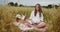 Young pregnant woman reading a book and smiling during picnic in a wheat field