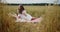 Young pregnant woman relaxing during picnic in a wheat field