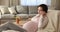 Young pregnant woman resting on armchair talking on the phone