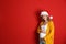 Young pregnant woman in Santa hat on red background. Christmas celebration