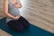 Young pregnant woman sat on mat doing prenatal yoga holding belly