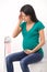 Young pregnant woman sitting in toilet. girl holding head and belly feeling headache