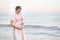 Young pregnant woman is standing on the seashore and hugging her belly. Enjoying the moment