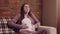 Young pregnant woman suffering from labor pain, sitting on couch at home, slow motion