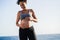 Young pregnant woman touching her belly while doing workout routing outdoor on the beach - Sport exercises and maternity concept