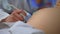 A young pregnant woman visits a doctor for an ultrasound screening. The doctor uses an ultrasound machine to examine the