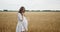 Young pregnant woman walking through a wheat field holding wheat bouquet