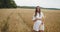 Young pregnant woman walking through a wheat field holding wheat bouquet