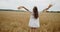 Young pregnant woman in white dress having fun in a wheat field