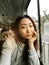 Young pretty asian woman traveling by train or bus, sitting near the window and taking selfie - enjoying travel.