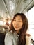 Young pretty asian woman traveling by train or bus, sitting near the window and taking selfie - enjoying travel.